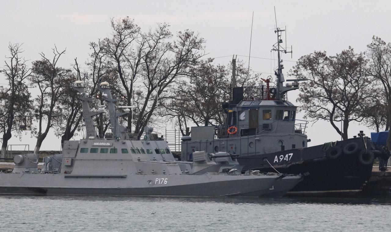 Seized Ukrainian ships, small armoured artillery ships and a tug boat, are seen anchored in a port of Kerch