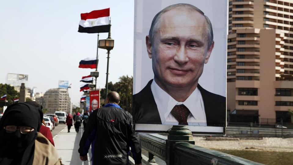 People walk past a banner with a picture of Russian President Vladimir Putin in central Cairo