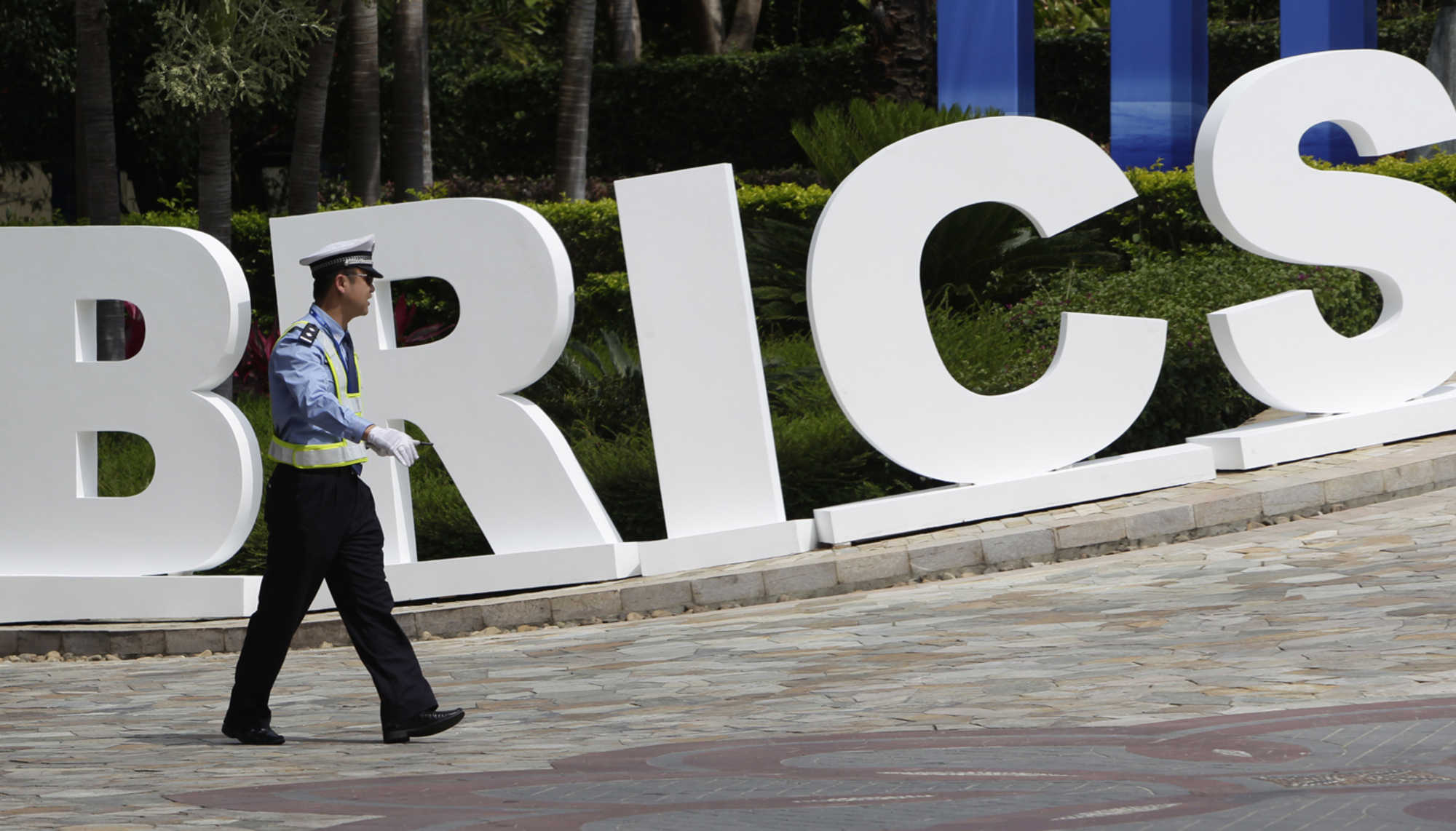 A traffic policeman walks past a signage for BRICS Summit in Sanya