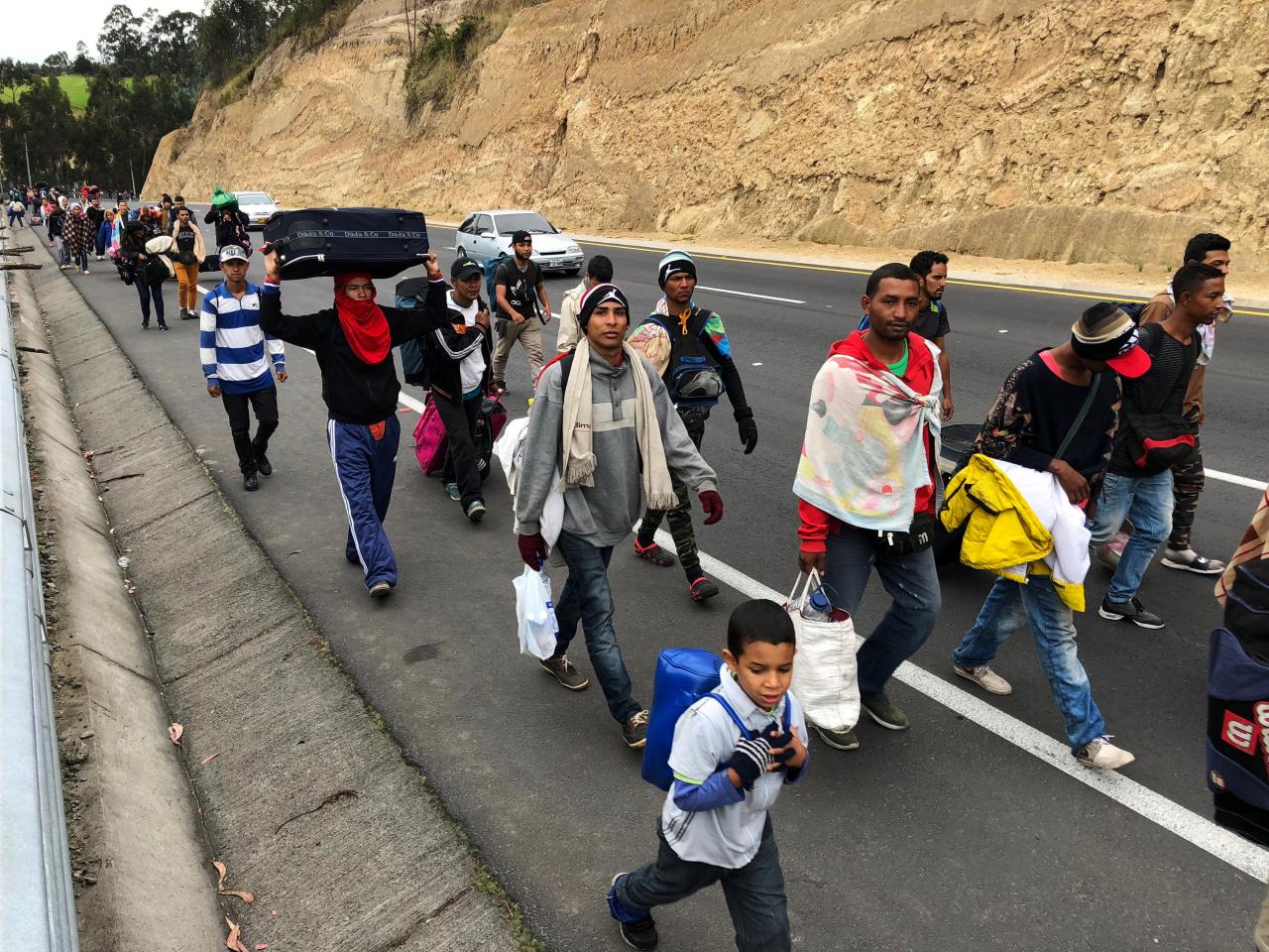 Venezuelan migrants walk along the Ecuadorean highway to Peru before new rules requiring they hold a valid passport kick in, at Tulcan