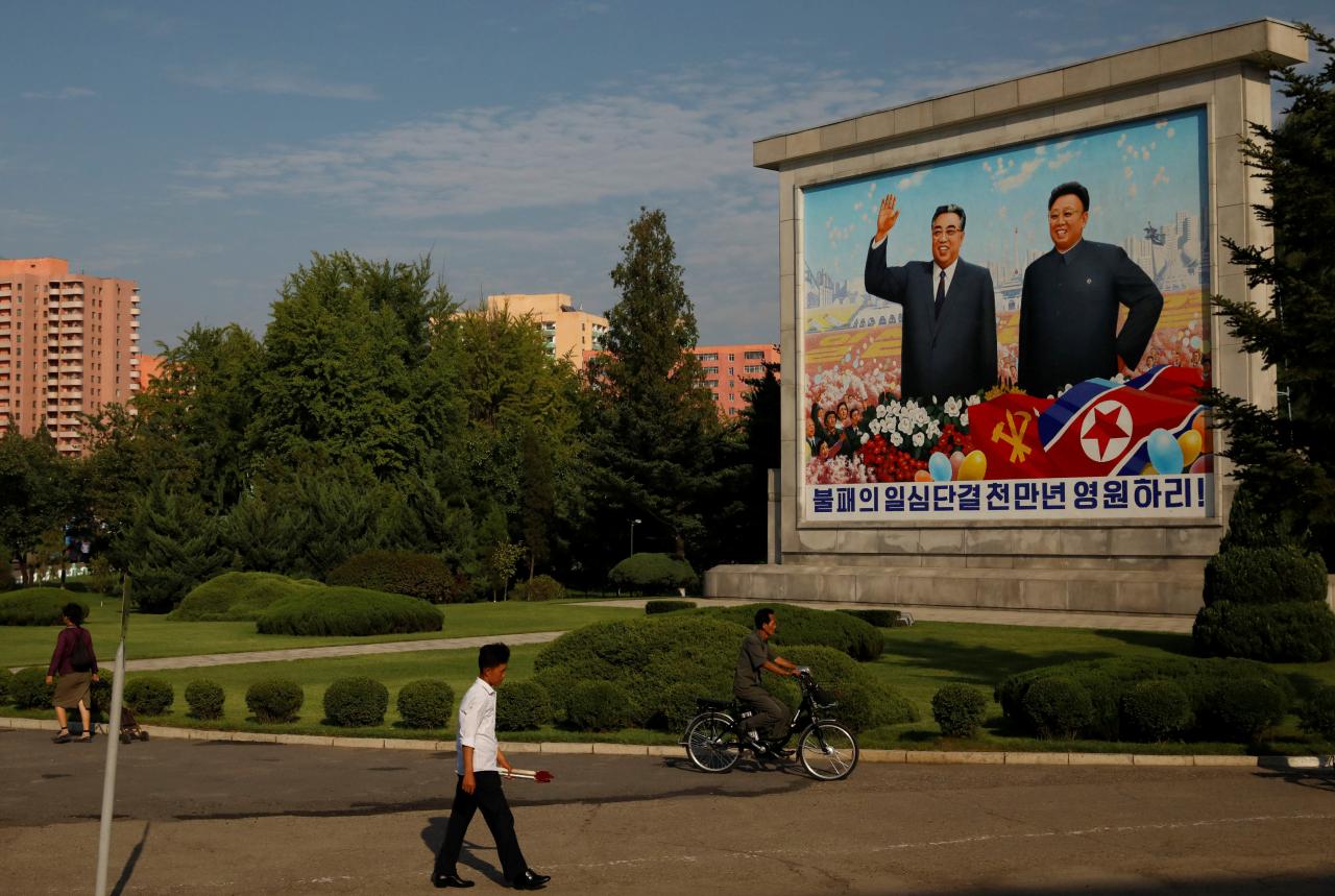 Residents pass by a painting featuring late North Korean leaders Kim Il-sung (L) and Kim Jong-il ahead of 70th anniversary of North Korea’s foundation in Pyongyang