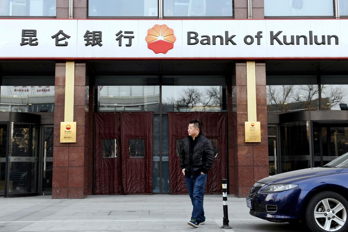 Man walks past a Bank of Kunlun branch in Beijing