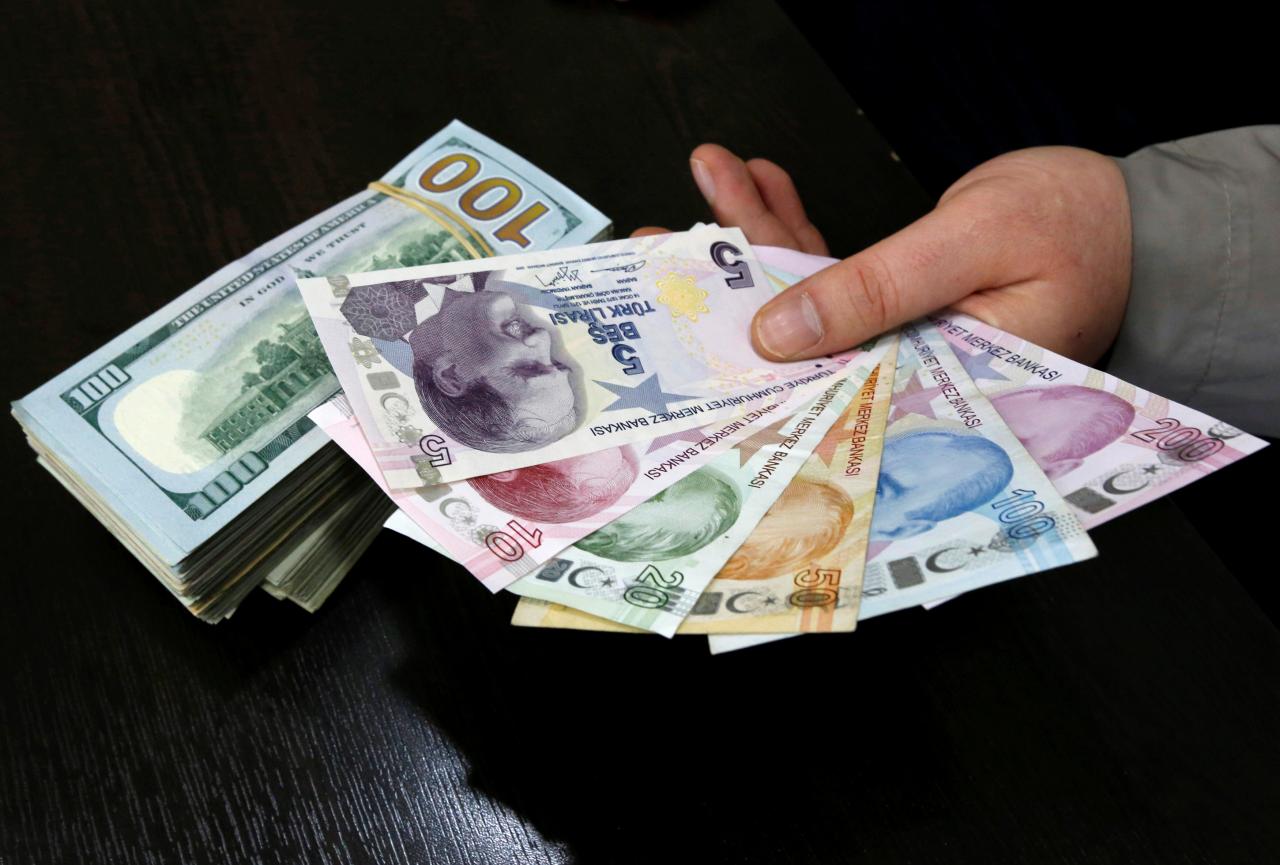 FILE PHOTO – A money changer holds Turkish lira banknotes next to U.S. dollar bills at a currency exchange office in central Istanbul