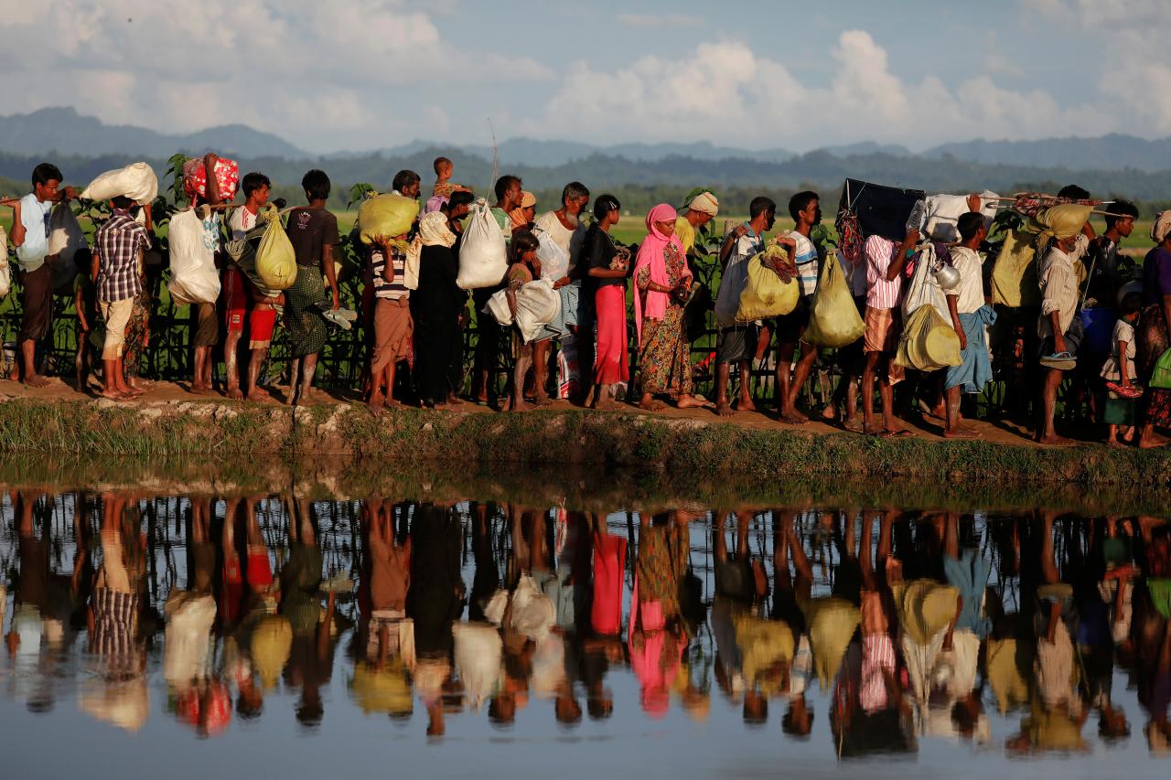 Rohingya refugees who fled from Myanmar wait to be let through by Bangladeshi border guards after crossing the border in Palang Khali