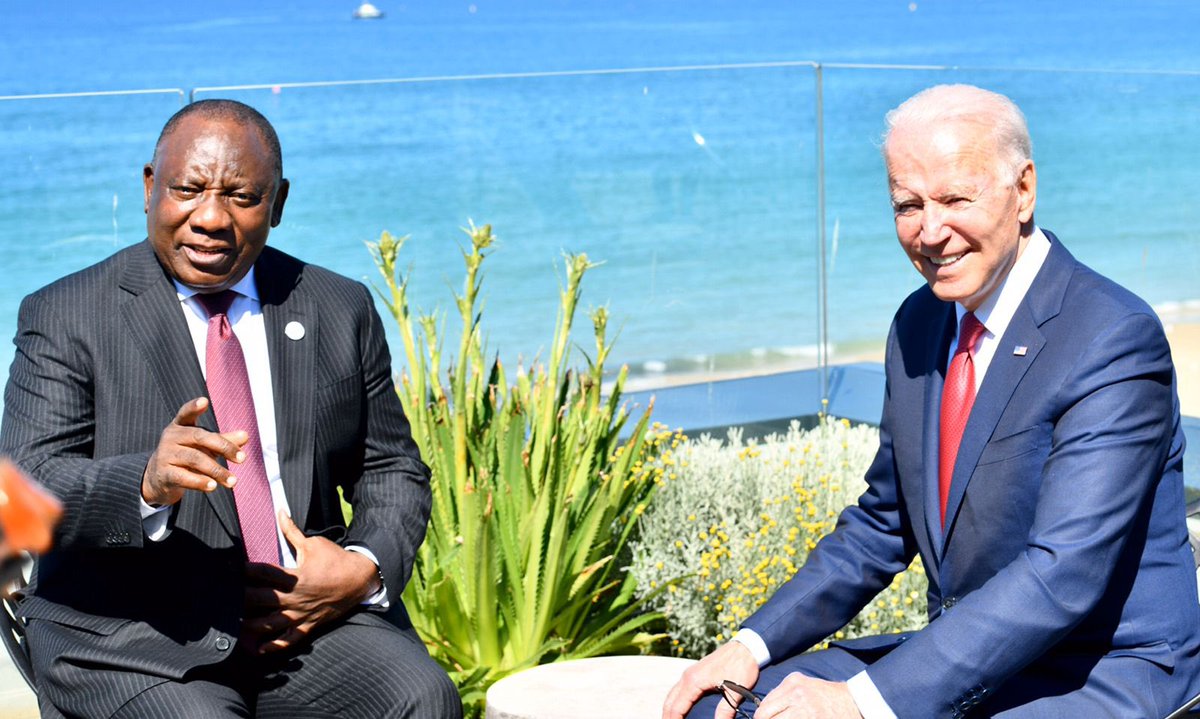 US President Joe Biden and South African President Cyril Ramaphosa sitting next to the water in conversation.